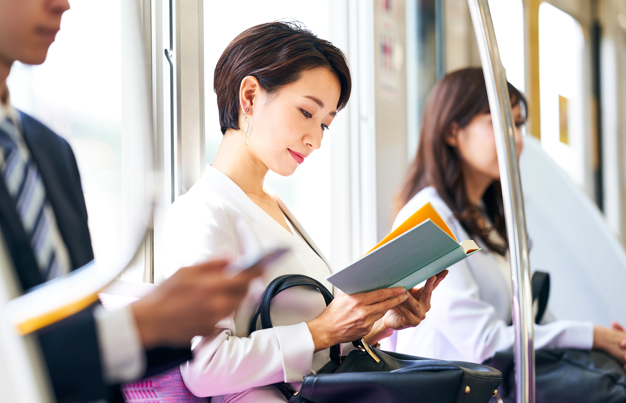 電車で座って本を読む女性