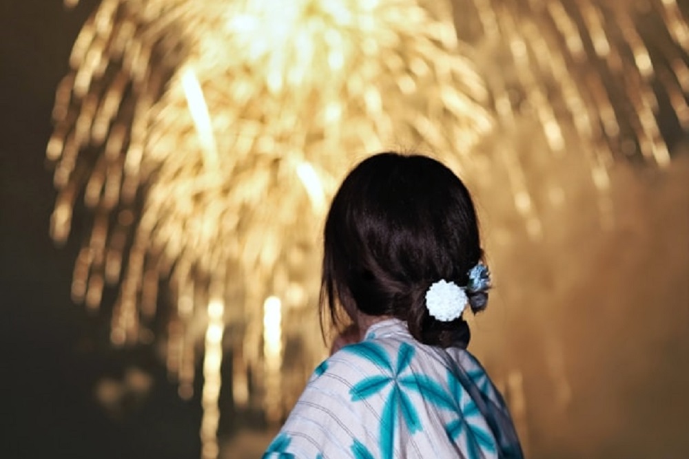 花火を見上げる浴衣姿の女性